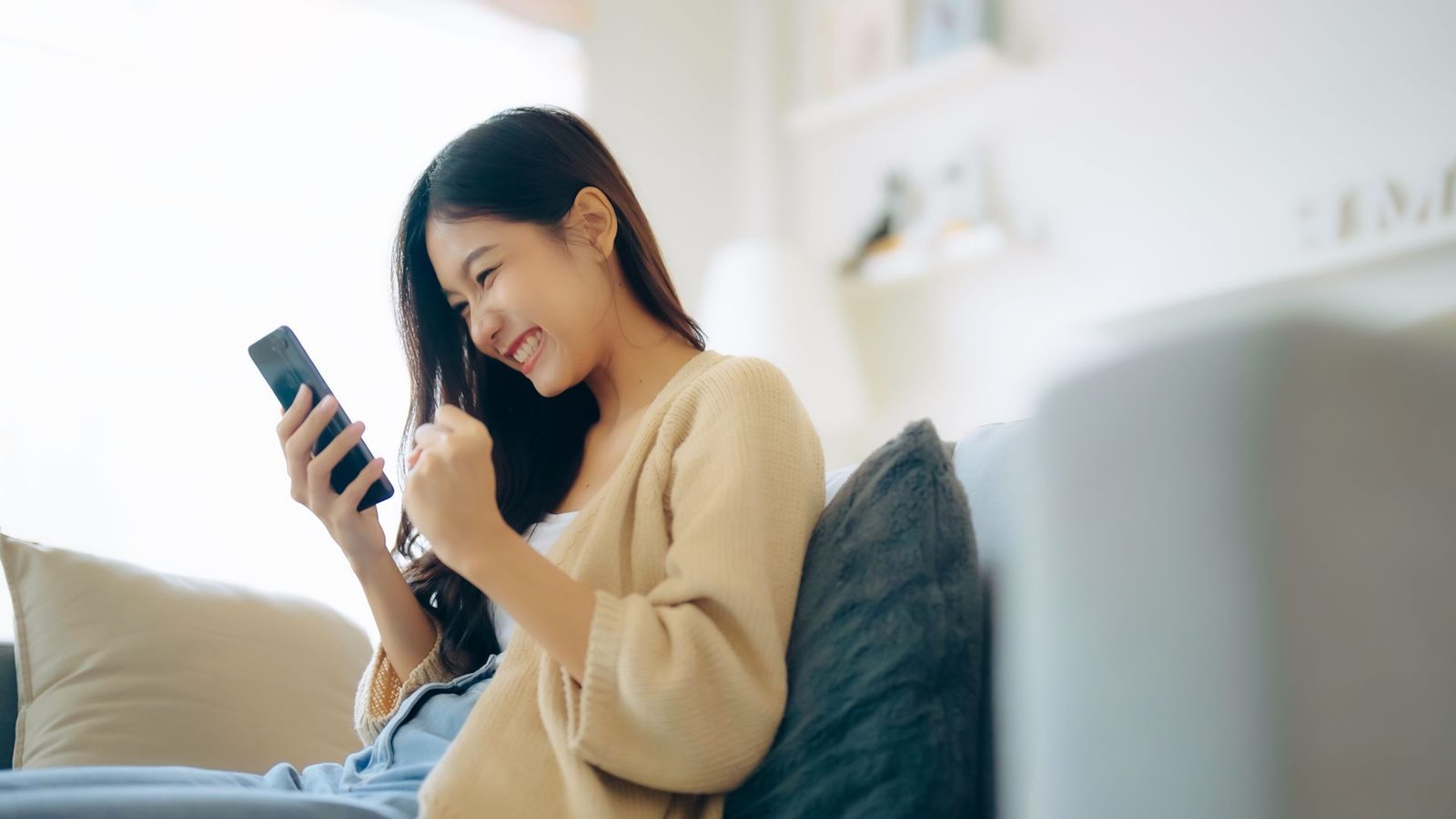 A woman is sitting on a couch looking at her cell phone.