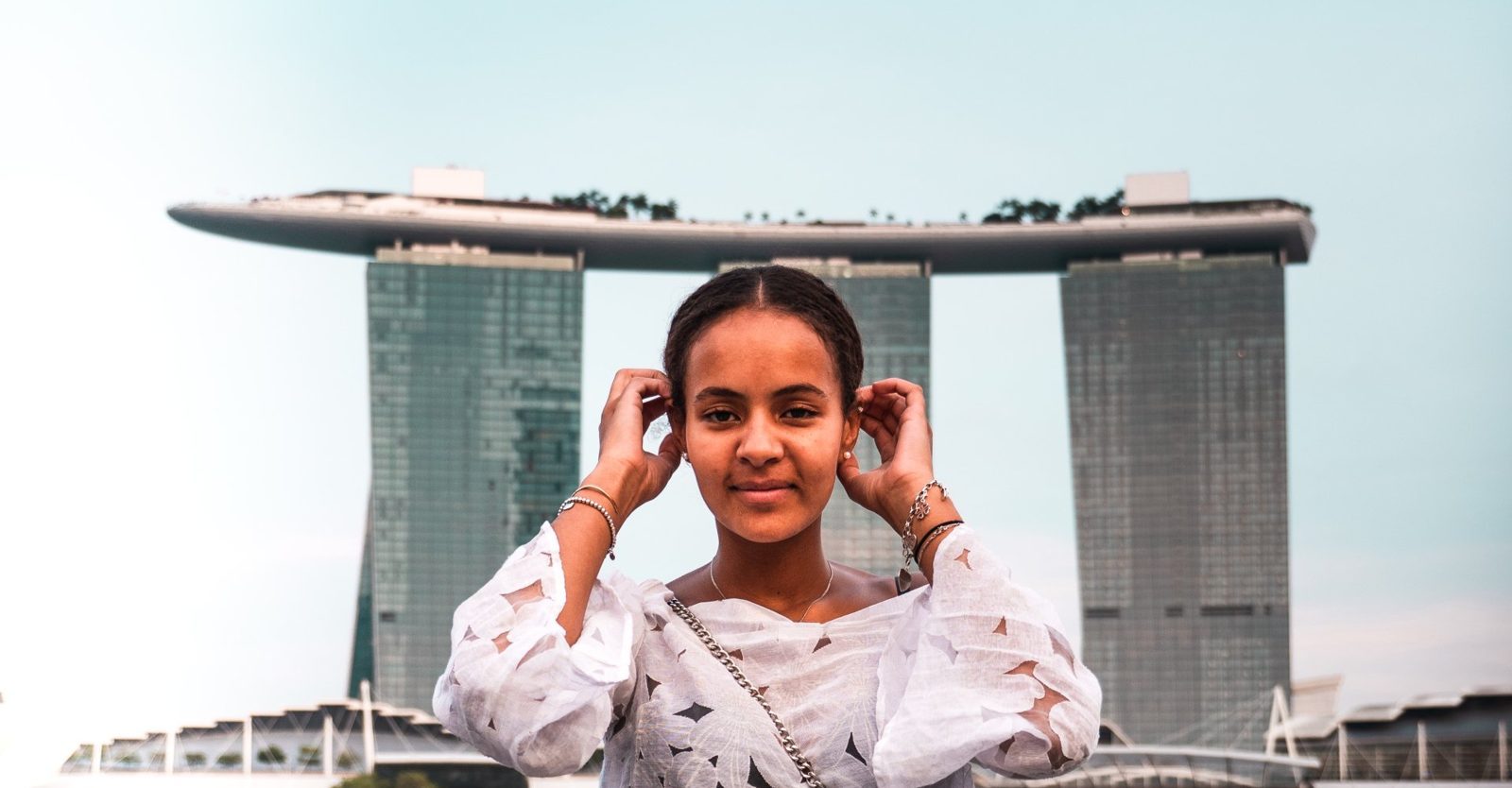 A woman is covering her ears in front of a building.