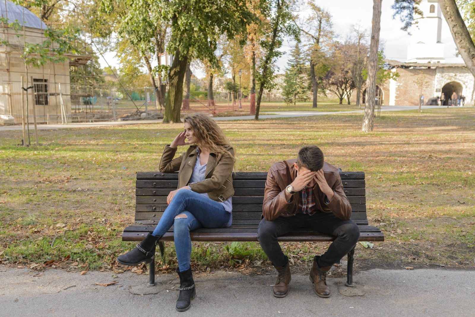 A man and a woman are sitting on a park bench.